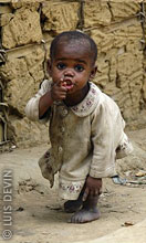 Pygmy child near a mud hut